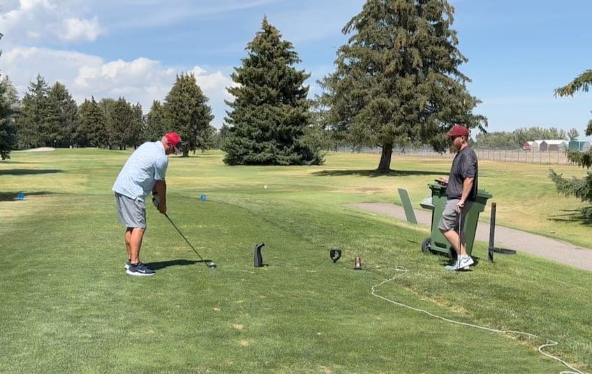 Golfer mid-swing on the tee box with the launch monitor set up alongside